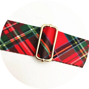 Detail of red and green plaid canvas strap with a polished gold adjustable metal buckle