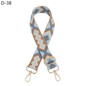 Detail of geometric diamond weave bag strap with golden metal hooks and adjustable buckle