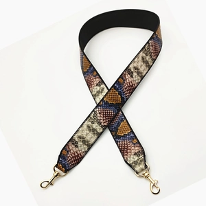 Close-up of wide snakeskin pattern purse strap with gold lobster claw clasps