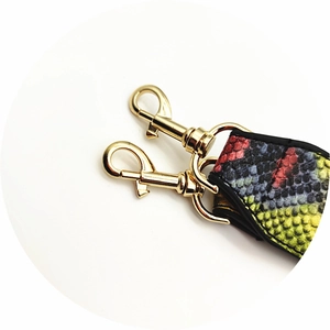 Detail of snakeskin textured colorful bag strap with golden metal lobster clasps
