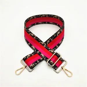 Detail of adjustable camo and red striped handbag strap with golden metal hooks