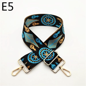 Detail of black woven shoulder strap with gold and blue geometric patterns and metal buckles
