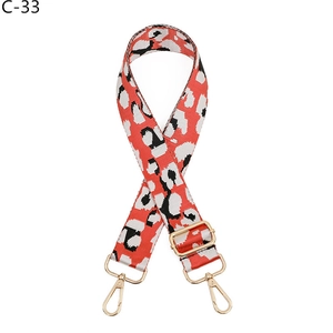 Detail of leopard print bag strap in orange and black with gold metal swivel hooks
