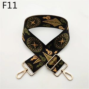 Close-up of ethnic style woven bag strap with green geometric patterns and gold buckles