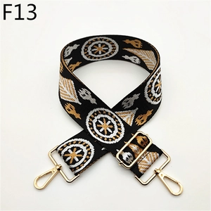 Close-up of adjustable wide woven shoulder strap with gold metal hooks and geometric patterns