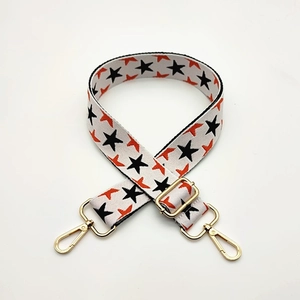 Adjustable wide woven bag strap with orange and black star patterns and gold hardware