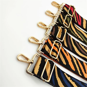 Detail of five colorful zebra striped canvas straps with gold metal hooks and buckles
