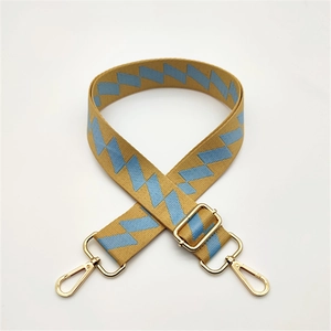 Detail of yellow and blue geometric woven bag strap with golden metal hardware hooks