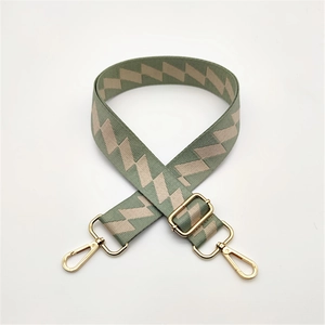 Detail of green and beige geometric woven bag strap with golden metal swivel hooks