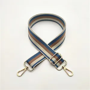 Detail of adjustable blue and brown striped woven shoulder strap with gold metal hooks