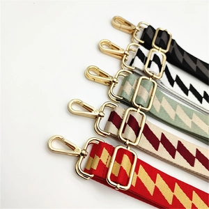 Detail of five nylon bag straps with geometric zigzag patterns and gold metal hooks
