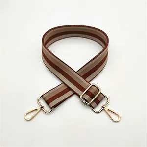 Adjustable striped fabric bag strap with golden metal hardware in brown and beige tones