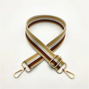 Detail of adjustable woven striped bag strap in yellow, beige and brown with gold hardware