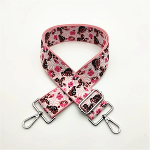 Detail of pink embroidered floral purse strap with polished silver metal hooks and buckle