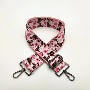 Detail of wide pink bohemian floral jacquard bag strap with grey metal lobster clasps