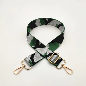 Détail d'une bandoulière de sac camouflage avec fil d'argent et mousquetons dorés