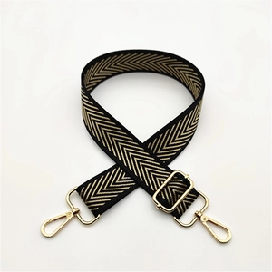 Close-up of herringbone pattern woven bag strap with adjustable gold metal buckle