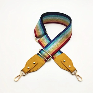 Detail of colorful rainbow striped bag strap with yellow leather and gold metal clips