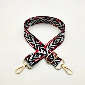 Macro detail of red black white geometric woven bag strap with golden metal swivel hooks