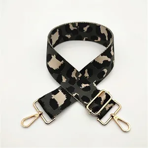 Macro detail of wide leopard print woven bag strap with golden metal hooks and buckles