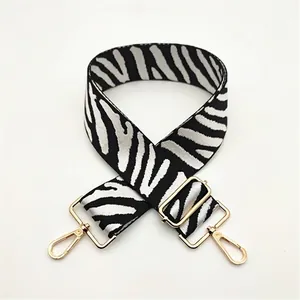Detail of adjustable zebra stripe wide bag strap with luxury gold metal hardware