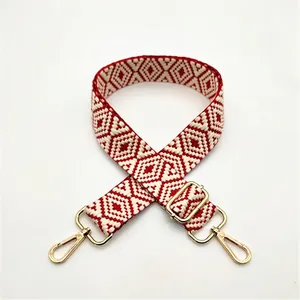 Detail of red and white geometric woven bag strap with golden metal swivel hooks and buckle