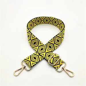 Detailed close-up of woven yellow and black geometric purse strap with gold metal buckle