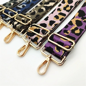 Detail view of five leopard print woven bag straps with gold metal hooks on white background