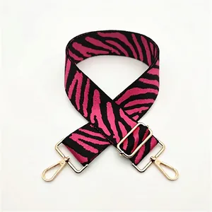 Detail of adjustable pink and black zebra pattern strap with gold metal hooks and buckle