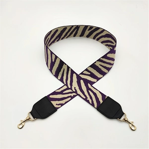 Detail of purple and beige zebra pattern wide jacquard shoulder strap with gold clips