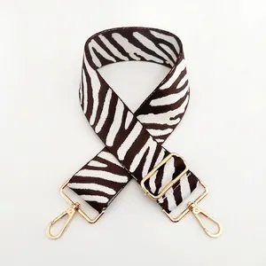 Detailed view of adjustable zebra print bag strap with polished gold-tone metal hardware