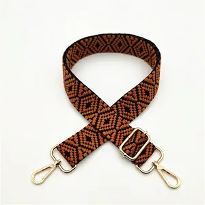 Close-up of adjustable woven shoulder strap with brown geometric diamond pattern and gold buckle
