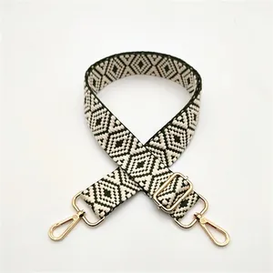 Close-up of geometric pattern woven shoulder strap with gold metal hooks for handbags