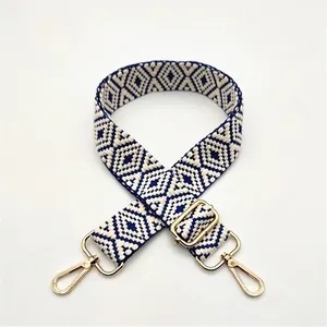 Detail of navy and beige geometric woven bag strap with adjustable gold metal buckle
