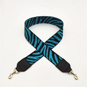 Detail of blue zebra pattern bag strap with black leather ends and golden metal hooks