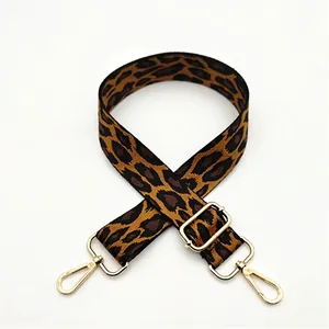 Close-up of leopard print polyester bag strap with golden metal swivel hooks and buckles