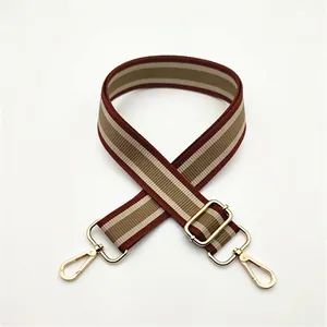 Close-up of adjustable striped fabric bag strap with golden metal swivel hooks