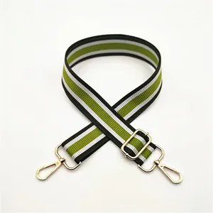 Detail of adjustable green and black striped shoulder strap with gold metal hooks