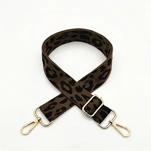 Detail of leopard print bag strap with polished gold-tone metal hooks and adjustable buckle