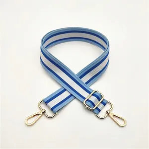 Adjustable blue and white striped bag strap with gold metal swivel hooks detail