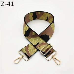 Close-up of camouflage woven bag strap with adjustable length and gold metal hardware