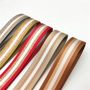 Detail view of woven bag straps with metallic gold thread and colorful stripes