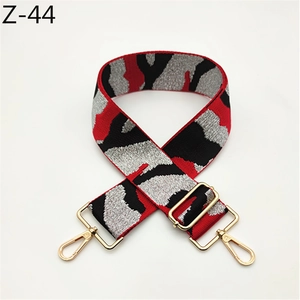 Detail of adjustable camouflage bag strap with red, black, silver weave and gold metal hooks