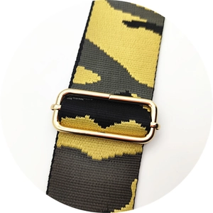 Detail of adjustable wide camouflage strap with polished gold metal buckle and texture