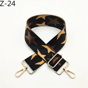 Detail view of colorful star pattern on wide nylon bag strap with gold metal hardware
