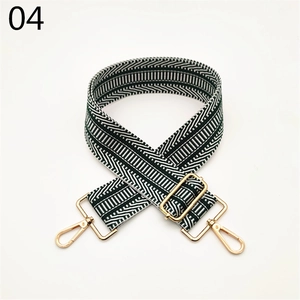 Macro detail of wide woven shoulder strap featuring green geometric patterns and gold metal hooks