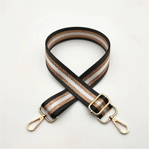 Close-up of adjustable striped handbag strap with gold metal hooks and glitter gold lines