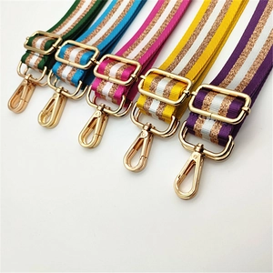 Close-up of colorful striped woven bag straps with gold glitter thread and metal hooks