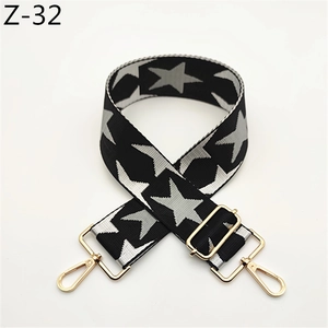 Close-up of wide canvas bag strap with black and grey star patterns and gold metal buckles