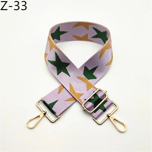Detail view of purple nylon bag strap with colorful star patterns and gold metal swivel hooks